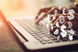 Hände auf Laptop mit Währungssymbolen als Symbol für P2P-Kreditplattformen.