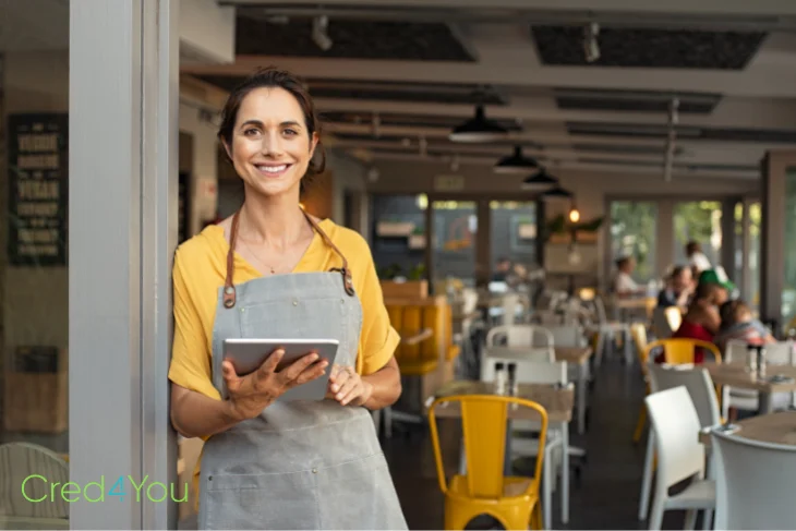 Frau mit Tablet im Café, Symbol für E-Rechnung und Kleinunternehmerregelung im Geschäftsalltag.